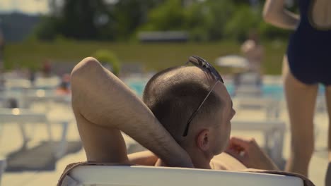 back view close-up bald married italian man is lying on beach on deck chair