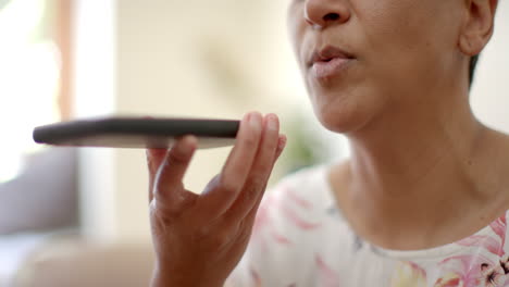 Feliz-Mujer-Birracial-Mayor-Sentada-En-El-Sofá-Y-Hablando-Por-Teléfono-Inteligente-En-Casa,-Cámara-Lenta