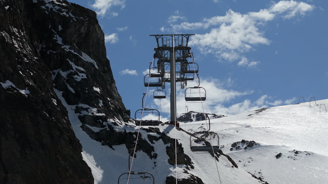 Ski lift ascending snowy Andes peaks, clear sky, winter, Cerro la hoya, adventure