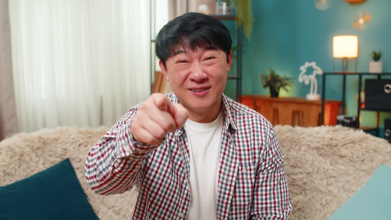 Asian man pointing finger at viewer in playful positive you gesture humorous engaging connection