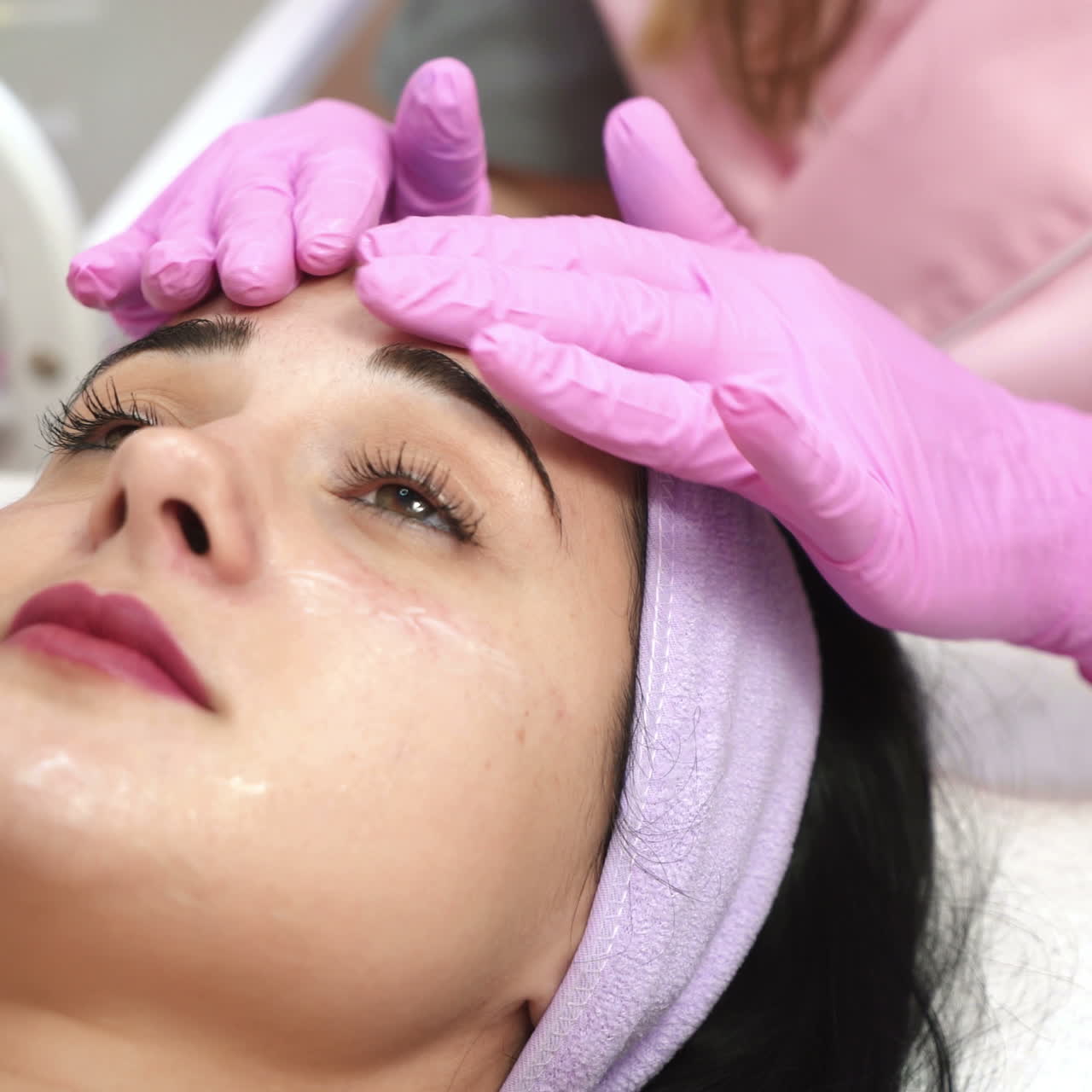 Beautiful young girl getting a facial cleansing procedure from a cosmetologist. Rejuvenating massage. Spa.