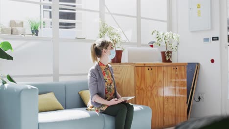 Office-colleagues-wearing-face-masks-greeting-each-other-by-touching-elbows-at-office