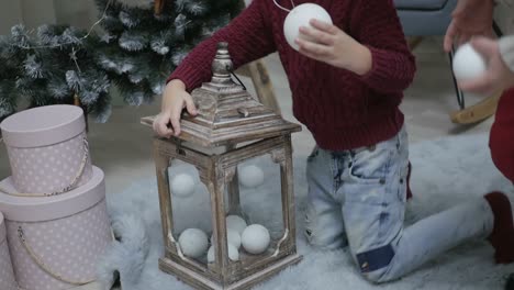 young boy decorating a christmas lantern with white ornaments