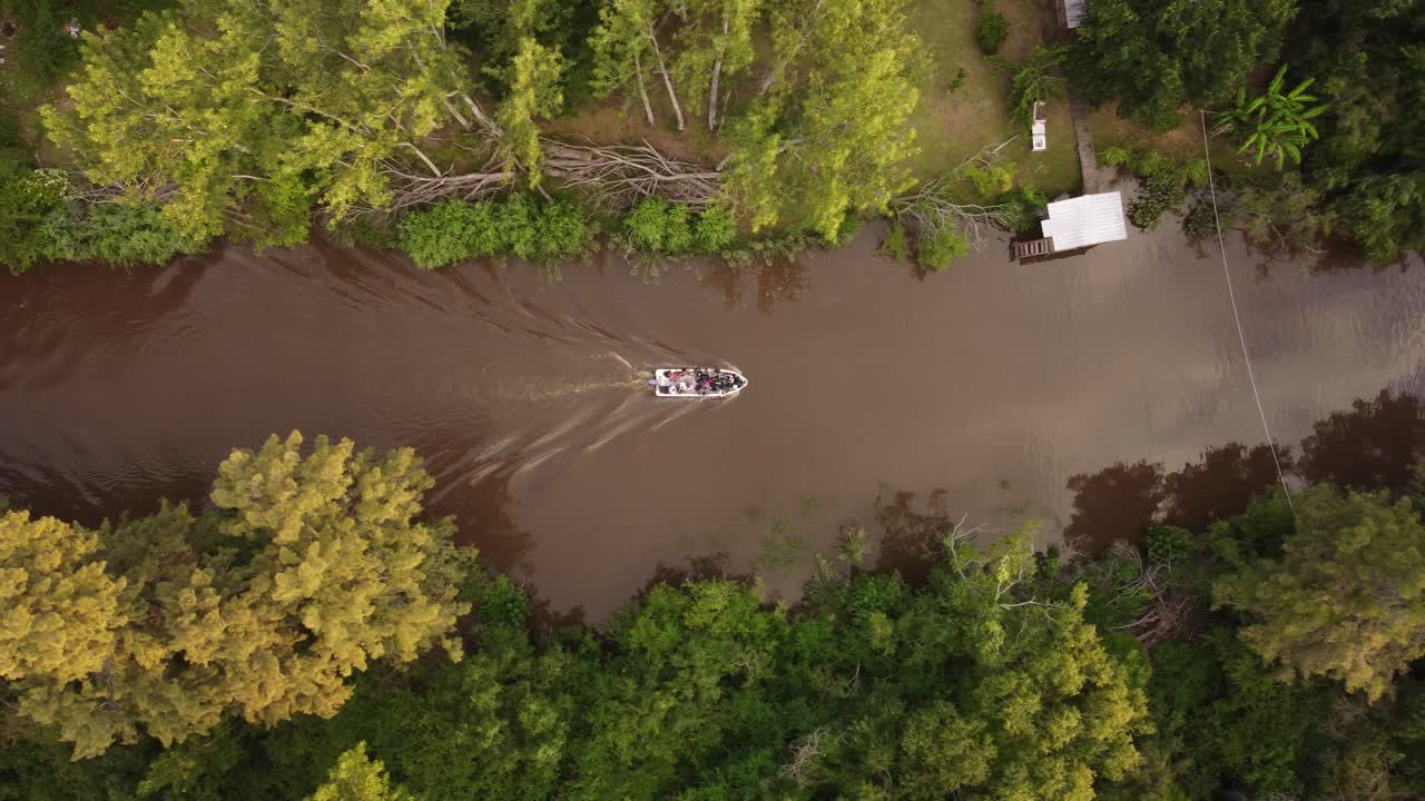 toma aérea de un barco de turistas cruzando un pequeño arroyo en el bosque amazónico