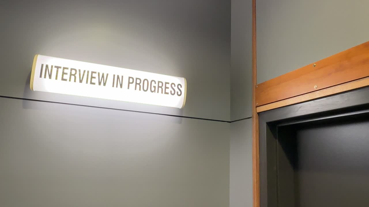 Job “Interview in Progress” lit-up sign above office - wide shot showing top of door