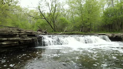 Bajo-A-La-Superficie-Del-Agua-Moviéndose-Y-Pasando-Por-Encima-De-Una-Pequeña-Cascada-De-Río-Forestal-En-Un-Parque-Rural