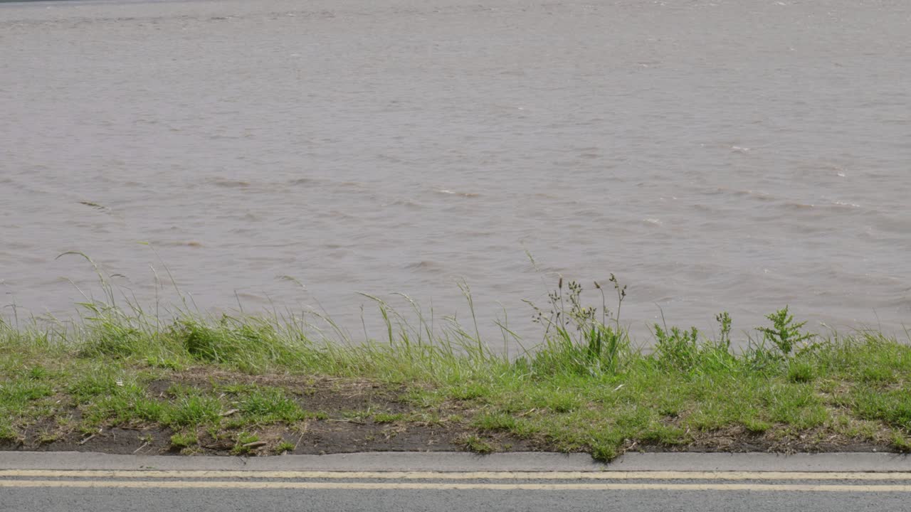 Grassy riverbank and quiet road at Hessle on a cloudy and calm day