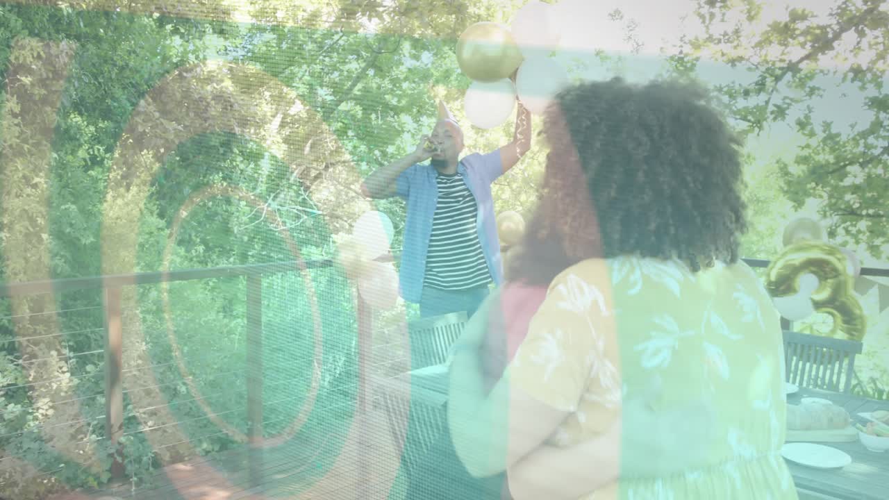 Two women approaching table on deck, event guests raising balloons and hugging, glass reflecting