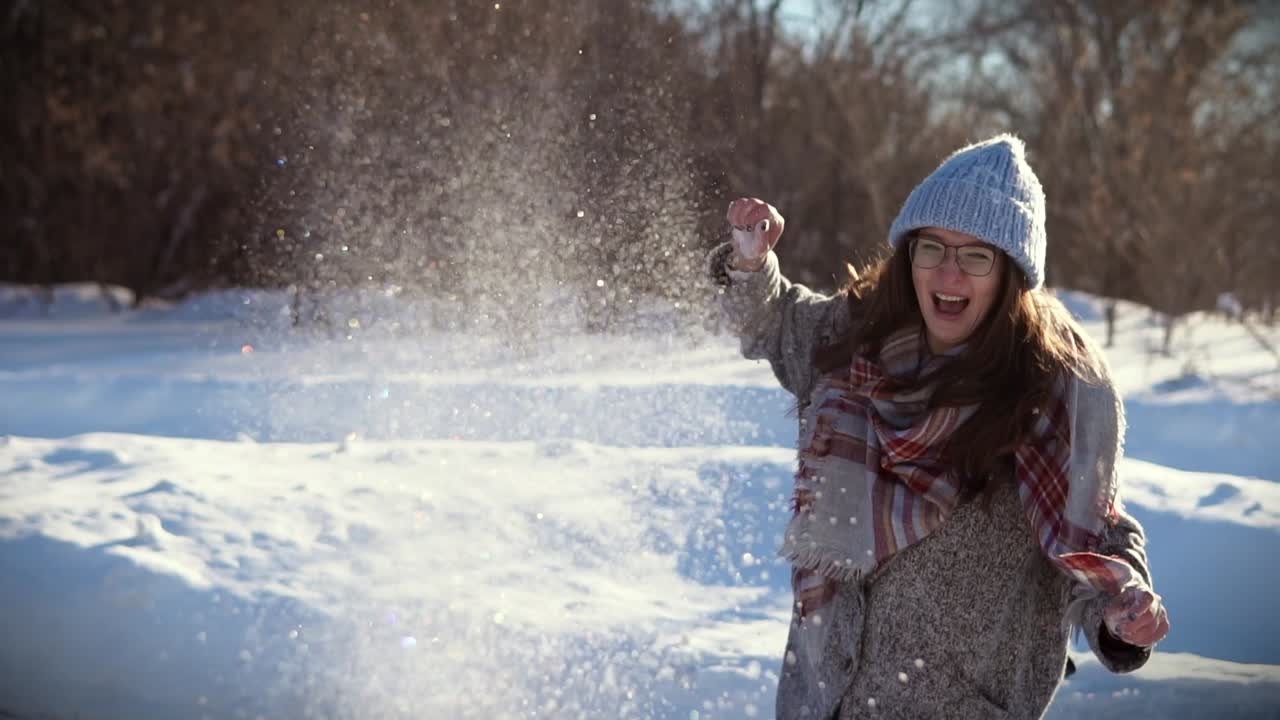 Woman having fun throwing snowballs in winter