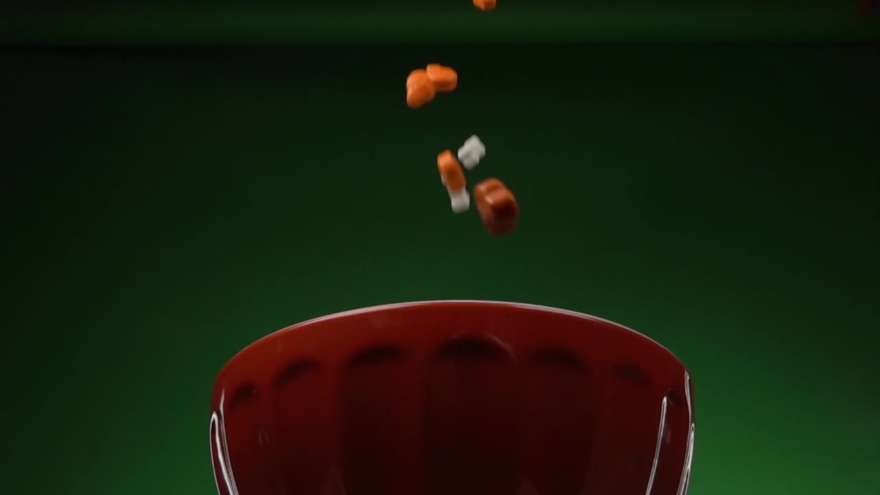 vista frontal de cráneos y huesos con forma de caramelo cayendo sobre un plato