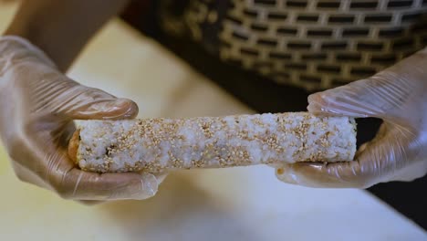 person's hands turning sushi roll , homemade preparation