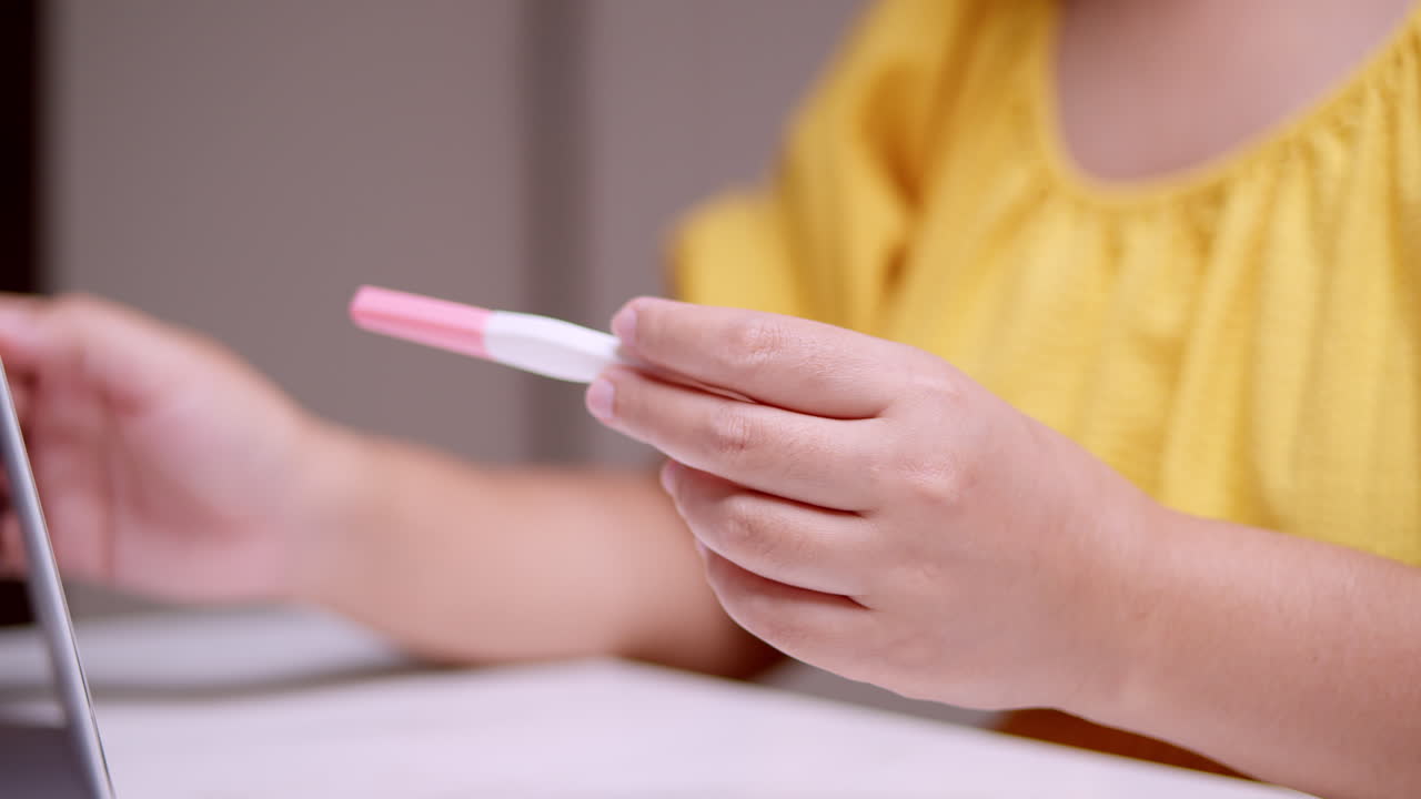 An expectant woman is holding a pregnancy test while counting the days and months prior to her possible delivery due date