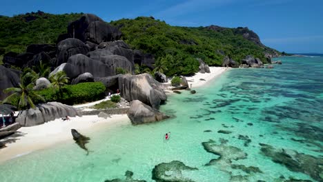 woman in red swim suit paddling in clear bottom kayak on la digue seychelles