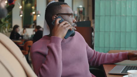 african businessman speaking on phone in cafe
