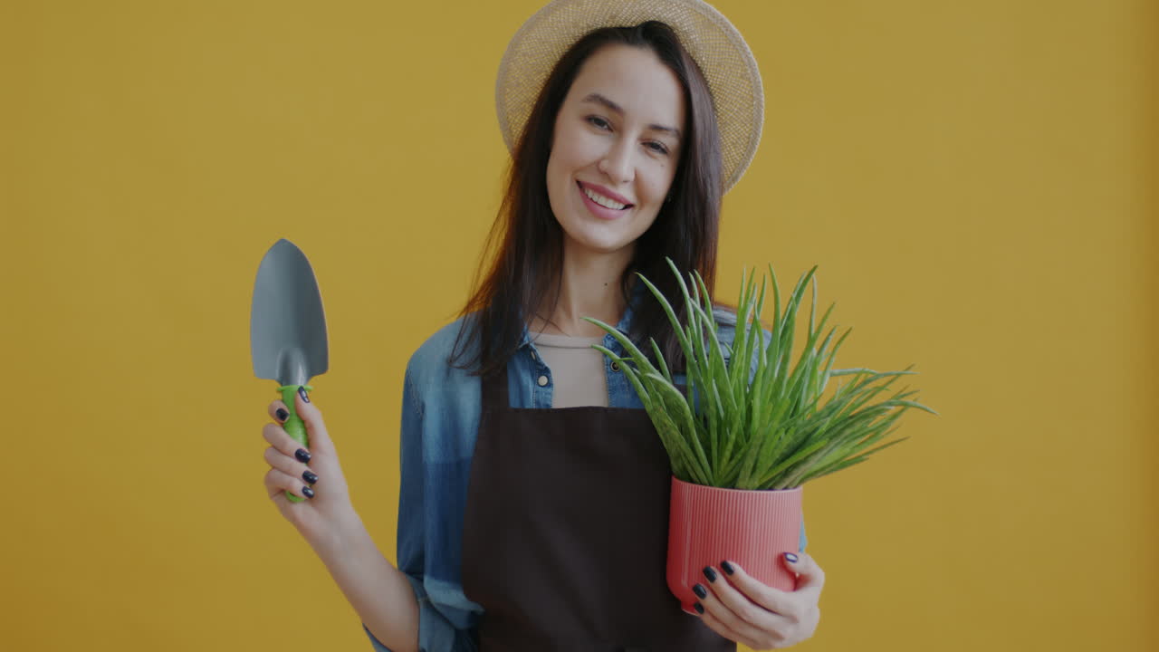Woman holding aloe vera plant and gardening tools