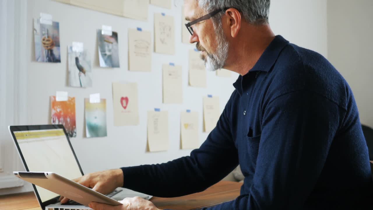 Man using laptop and digital tablet at home 4k
