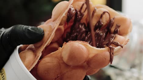 pouring melted chocolate on a waffle in a pastry shop