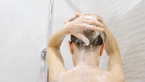 a woman washes her hair with shampoo
