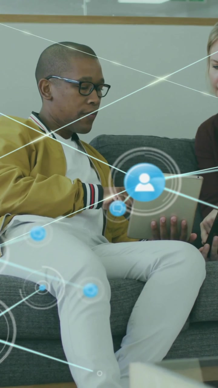 Animation of network of connections with icons over diverse colleagues using tablet in office