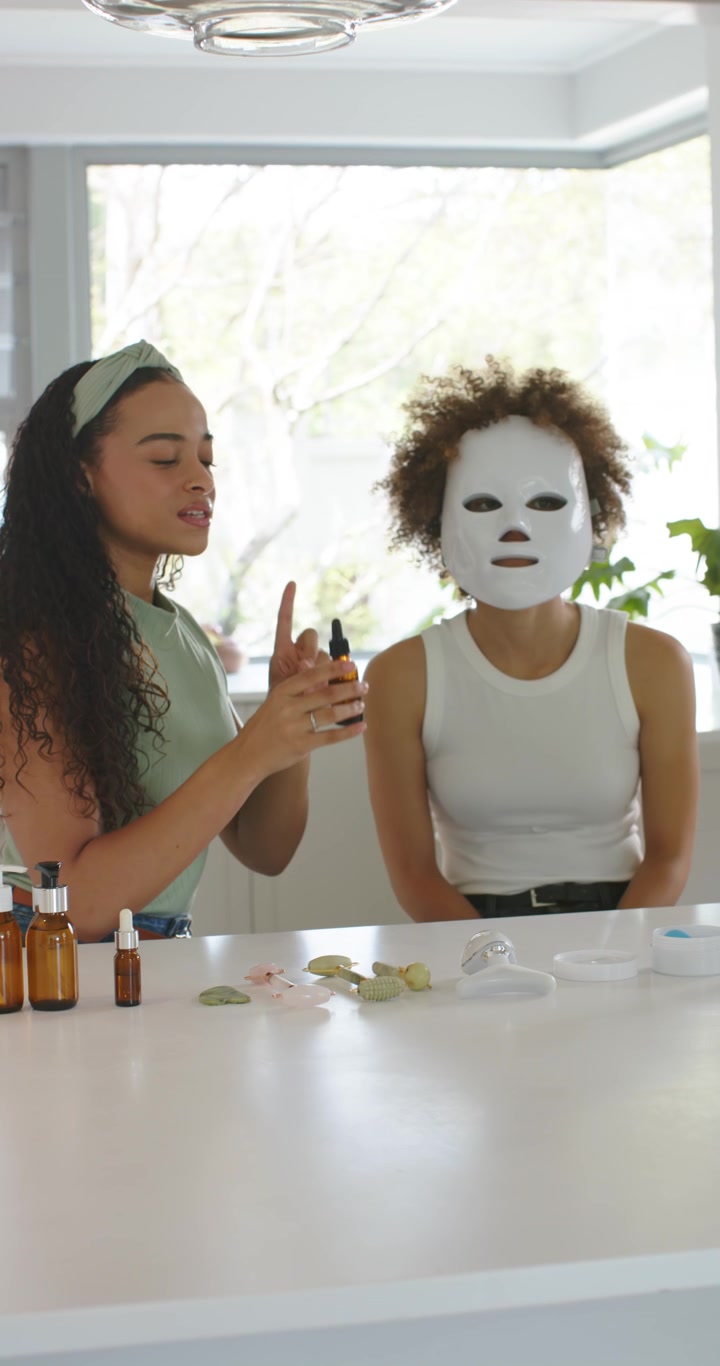 Video verticale: Conduttrice afroamericana che indica e applica un contagocce ambrato su una maschera su un'isola