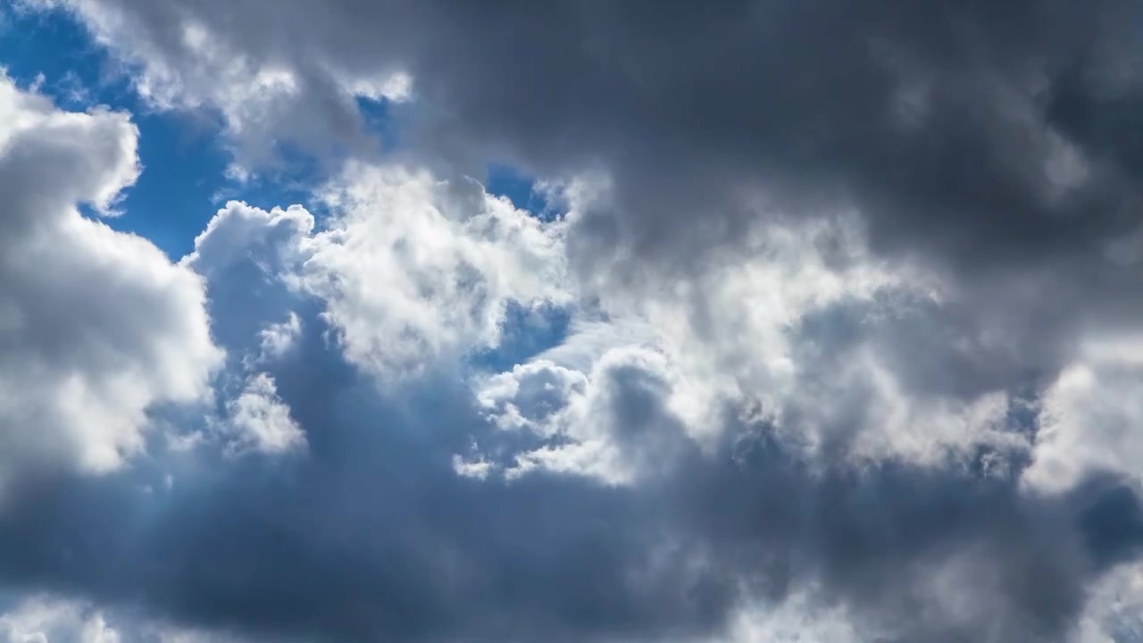 Nuvole bianche con grandi ombre che entrano ed escono dall'inquadratura davanti a un cielo blu durante una giornata bella ma piovosa