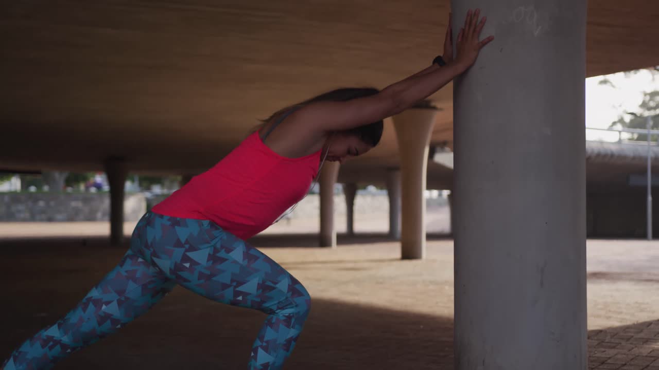 Caucasian woman stretching under a bridge