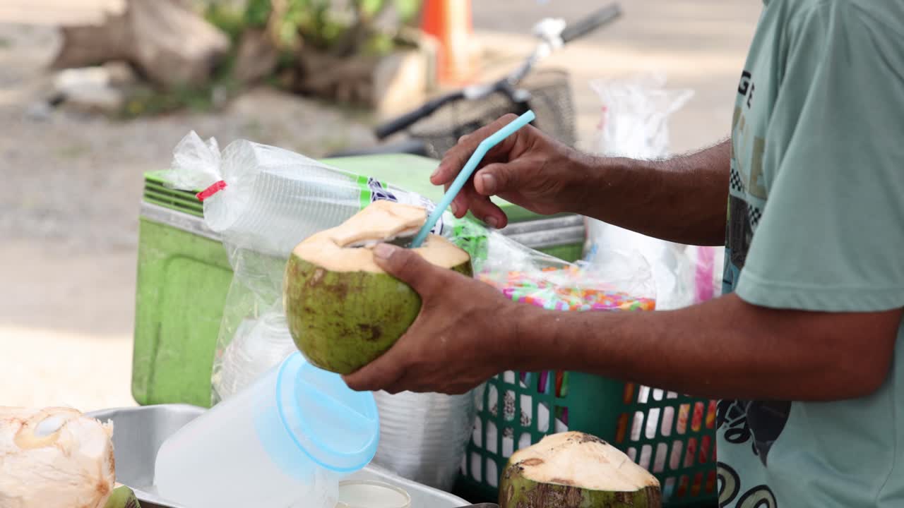 persona cortando abierto y bebiendo agua de coco fresca.