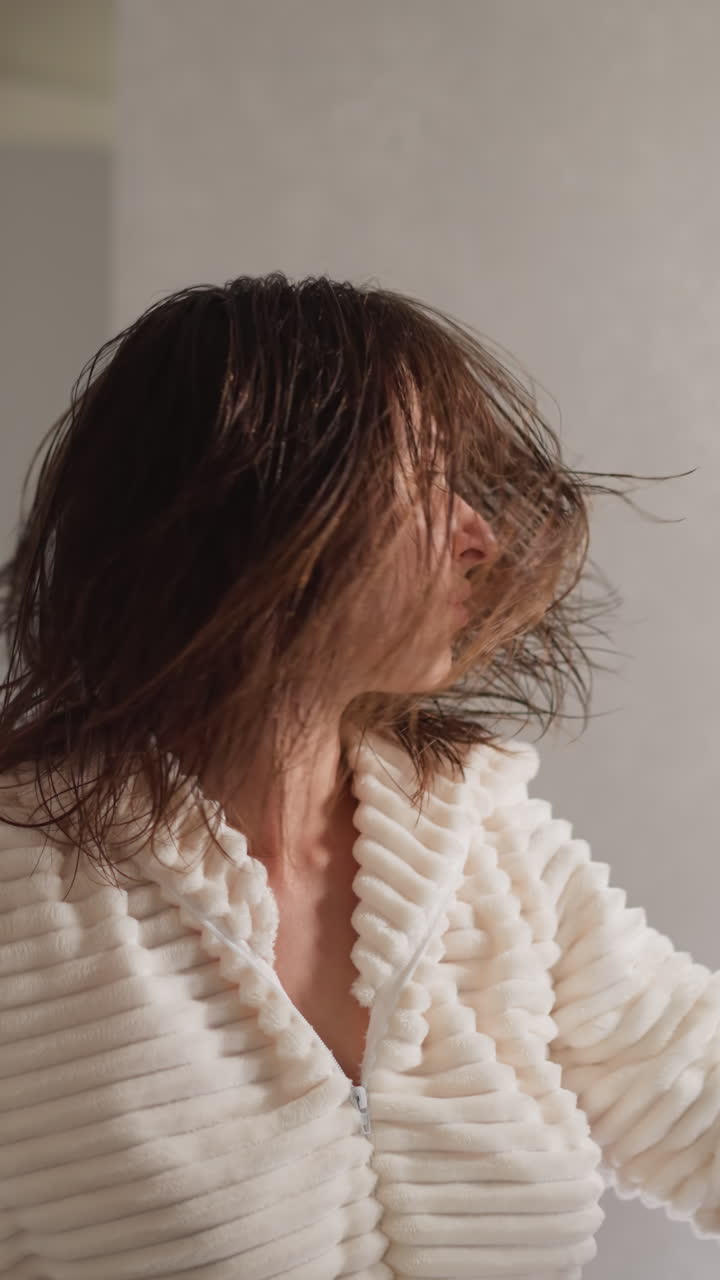 화장실에서 음악을 듣고 있는 여성, 어두운 머리카락을 가진 갈색 여성, 현대적인 화장실의 느린 동작에서 즐거운 음악을 듣는 여성.