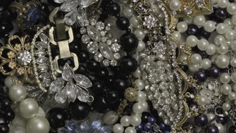 conjunto de joyas, fondo de rotación de oro amarillo y blanco. muchas hermosas joyas de moda femeninas con piedras preciosas brillantes, perlas y diamantes para mujeres. riqueza y concepto de lujo, primer plano, macro