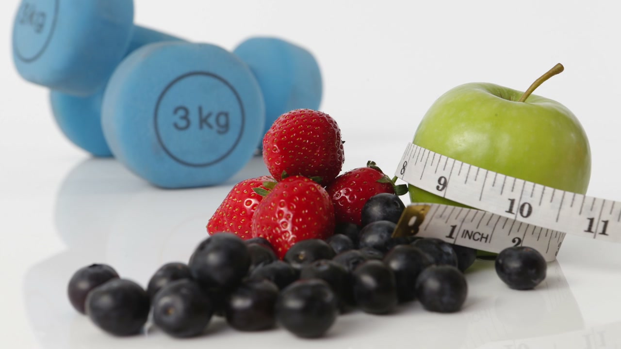 Sequenza in stop motion di frutta, manubri e metro a nastro