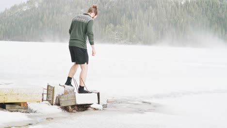 man walking on broken wooden jetty from the frozen lake of trondheim, norway