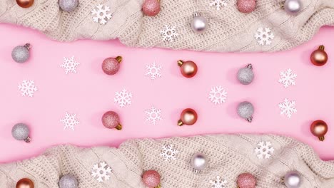 winter christmas decoration with knitted sweater and ornaments on pink theme. stop motion