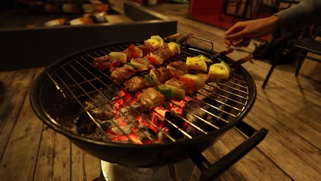 turning skewers over glowing charcoal embers