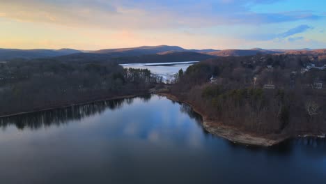 Aerial-drone-footage-of-lakes,-hills,-mountains,-and-forests-during-sunset-in-the-Appalachian-mountain-during-winter