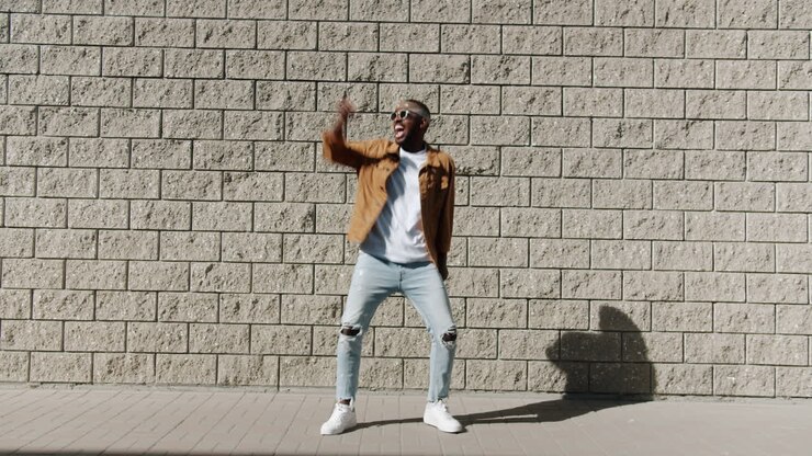 Man Dancing in Front of Brick Wall