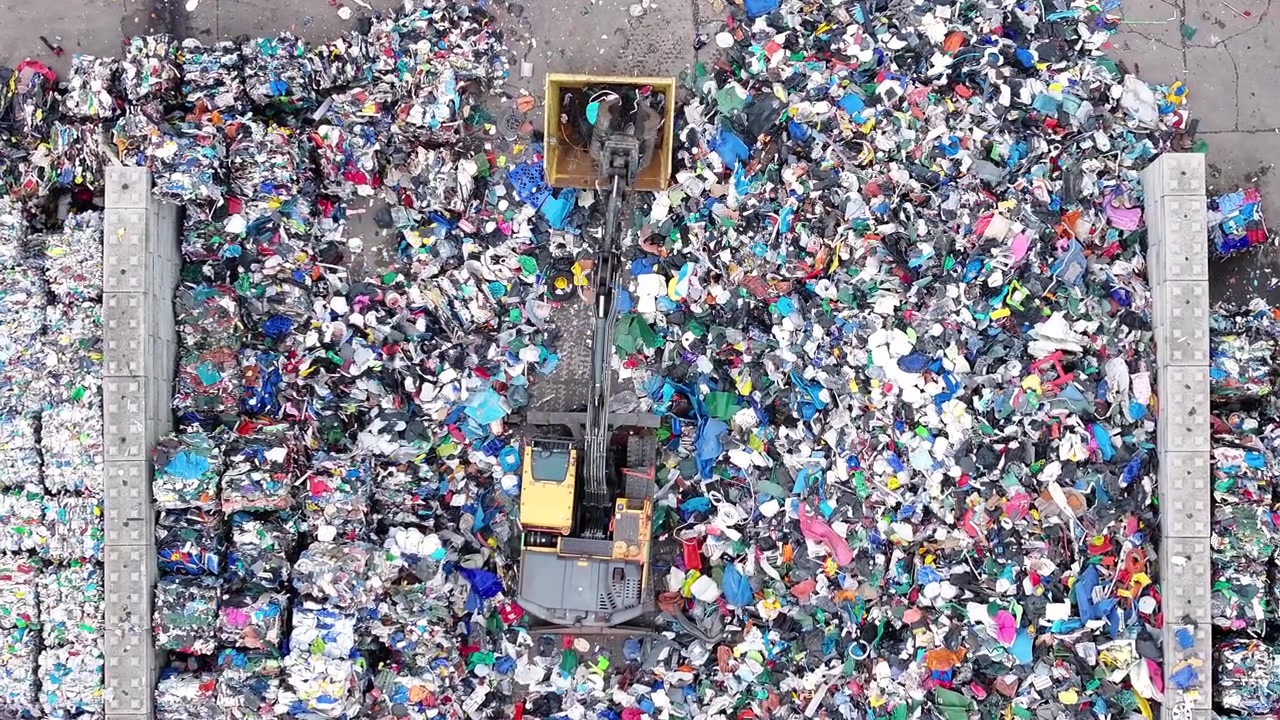Workers sort and process plastic waste at a recycling facility. Machines separate recyclable materials from non-recyclable materials for proper disposal and recycling.