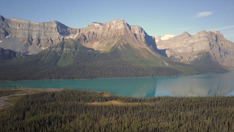 aerial reveal, pulpit peak and surrounding rockies reflecting in the calm waters of hector lake, alberta canada