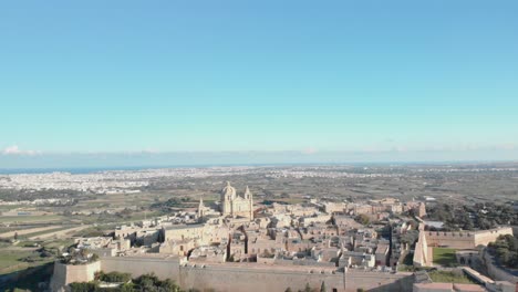 aerial shot of the whole fortified silent city, mdina in with a view of the island malta in the surrounding on a bright sunny calm day.