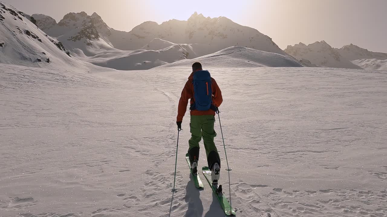 guía de esquí solitario que sube a la cima de la montaña