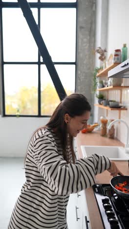 woman cooking red peppers in a kitchen