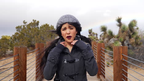 Attractive-young-woman-in-a-freezing-cold-and-windy-storm-with-a-colorful-rainbow-in-the-cloudy-sky-SLOW-MOTION