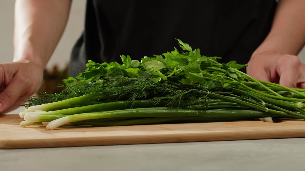 Cutting fresh green onions on a cutting board, close up chef cooking green vegan salad.