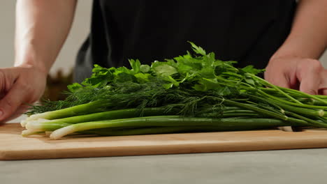 cutting fresh green onions on a cutting board, close up chef cooking green vegan salad.