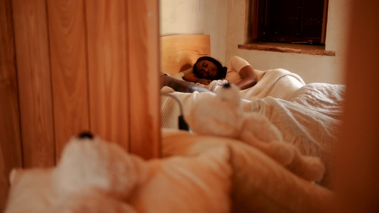 Soveværelsesspejlbillede af familie med børn, der sover i sengen.