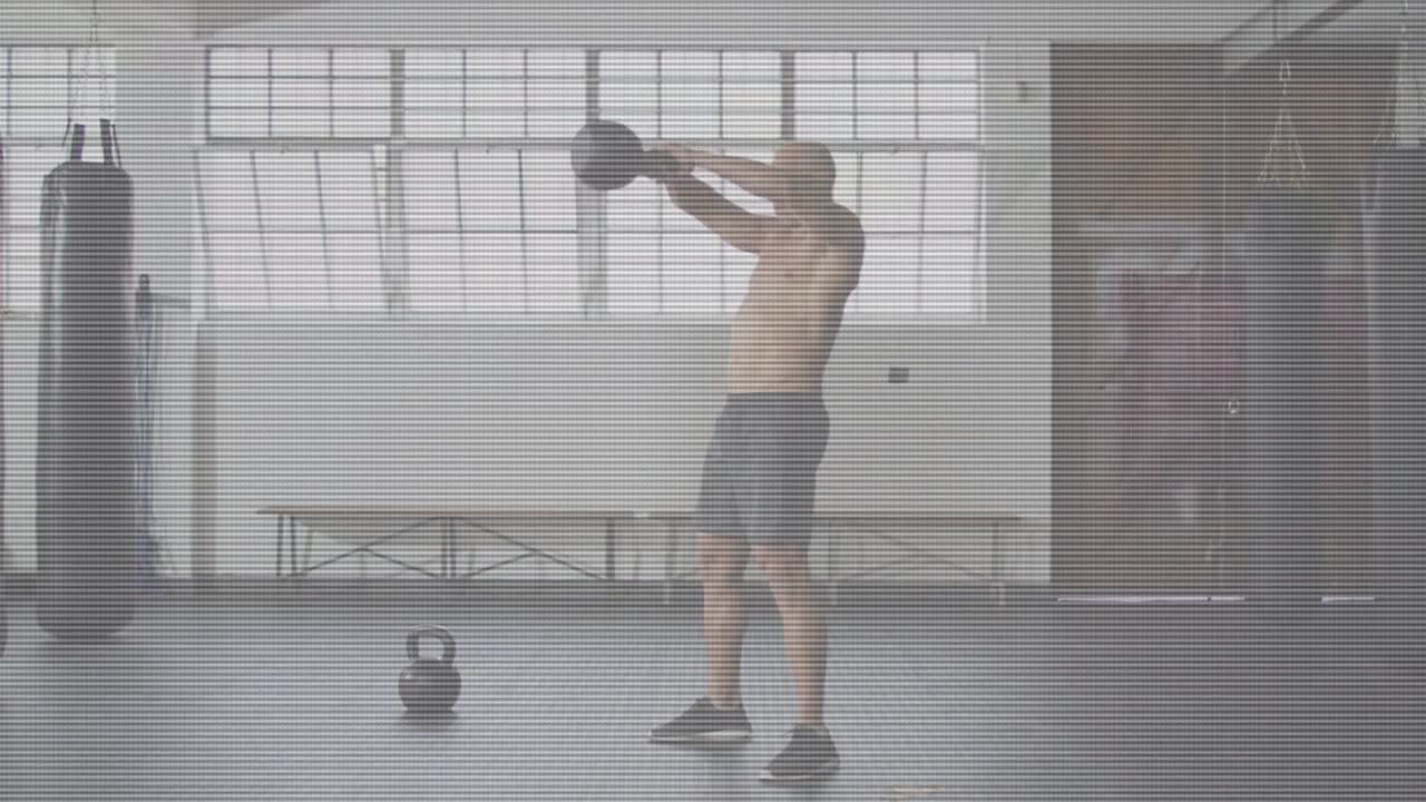 Un uomo si avvicina a un kettlebell e afferra la maniglia, eseguendo oscillazioni e spinte esplosive per il fitness.