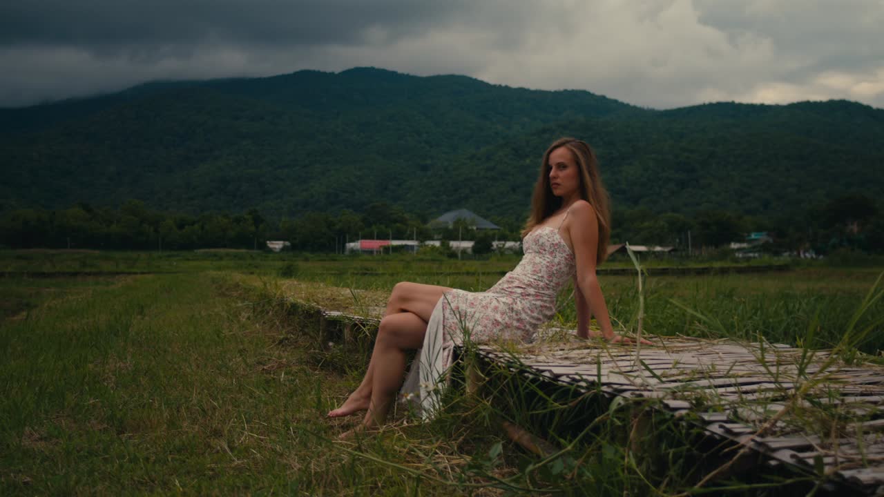 Woman Sitting on Wooden Walkway in Rice Paddy Field