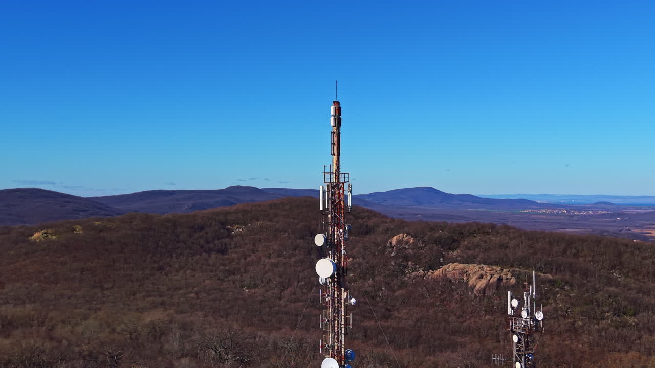 Torri di comunicazione su una cresta montuosa con cielo azzurro limpido e colline in lontananza sullo sfondo durante il giorno