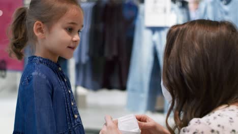 madre aplicando una máscara protectora para el virus a su hija linda