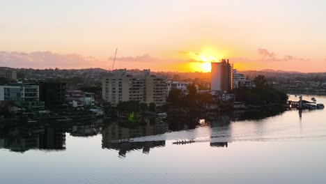 Tres-Botes-De-Remos-De-Cuatro-Personas-Están-Corriendo-Por-Un-Río-Tranquilo-De-Brisbane-Mientras-Los-Amaneceres-En-La-Distancia