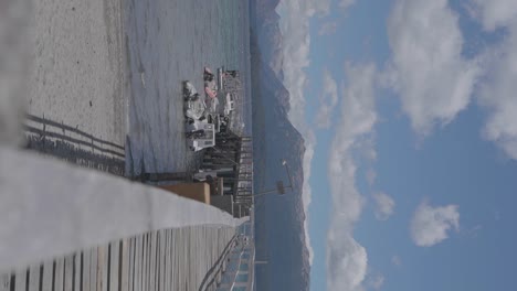 A-tranquil-wooden-pier-and-boats-on-a-lake-with-mountains-and-clouds-in-the-background